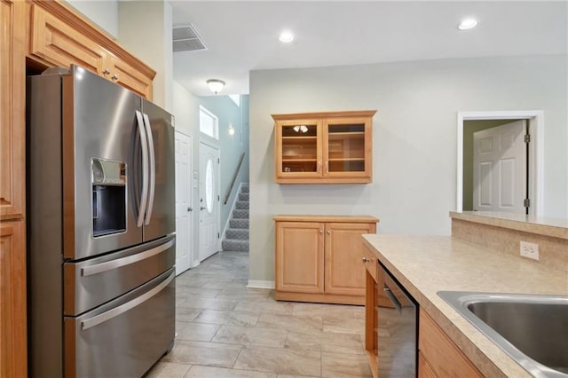 kitchen with appliances with stainless steel finishes, light tile patterned flooring, and light brown cabinetry