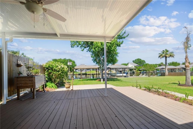 deck featuring a water view, a lawn, and ceiling fan