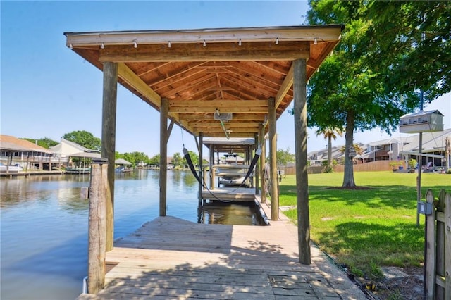 view of dock with a lawn and a water view