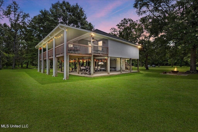 back house at dusk featuring a yard, a deck, and a patio area