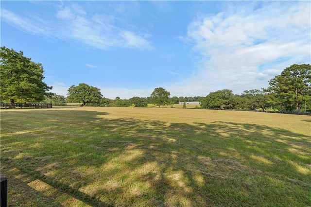 view of yard with fence and a rural view