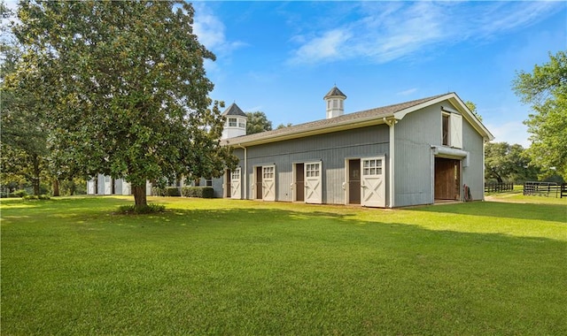 back of property with a garage, a yard, and an outbuilding