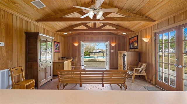 interior space featuring visible vents, wood walls, ceiling fan, tile patterned floors, and french doors