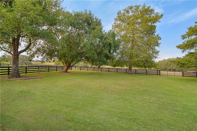 view of yard with fence and a rural view