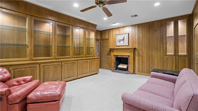 carpeted living room with ceiling fan, crown molding, and wooden walls