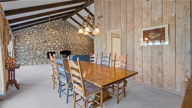 carpeted dining space with wooden walls, lofted ceiling with beams, and a chandelier