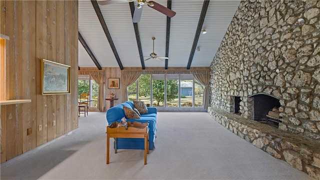 carpeted living room featuring a healthy amount of sunlight, wooden walls, a fireplace, and high vaulted ceiling