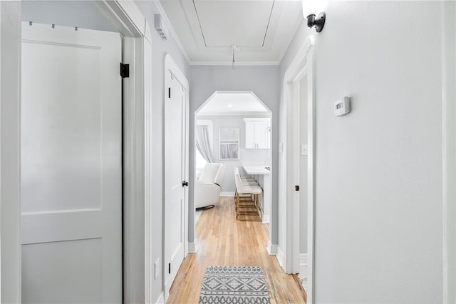 hallway featuring crown molding and light hardwood / wood-style flooring