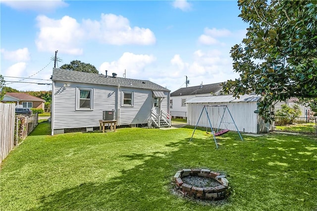 rear view of property with a yard, a storage shed, and a fire pit