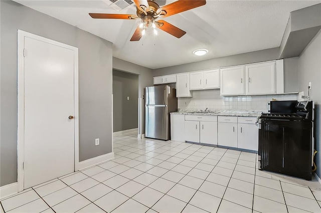 kitchen featuring stainless steel fridge, backsplash, black stove, white cabinetry, and sink