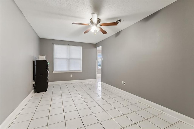 tiled spare room with ceiling fan and a textured ceiling