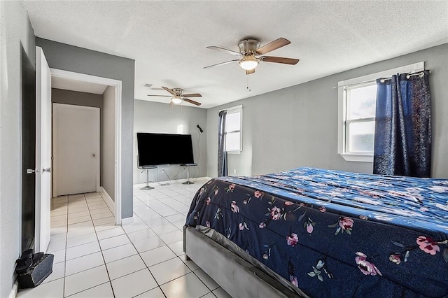 bedroom featuring ceiling fan, a textured ceiling, and light tile patterned floors