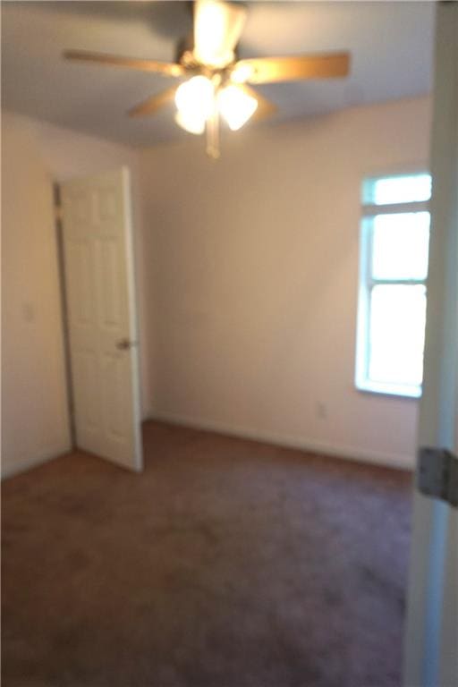 unfurnished bedroom featuring dark carpet and ceiling fan