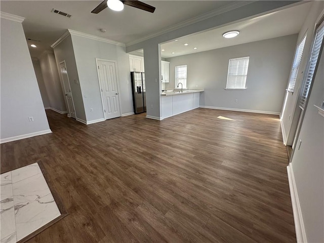 unfurnished living room with sink, crown molding, ceiling fan, and dark hardwood / wood-style flooring