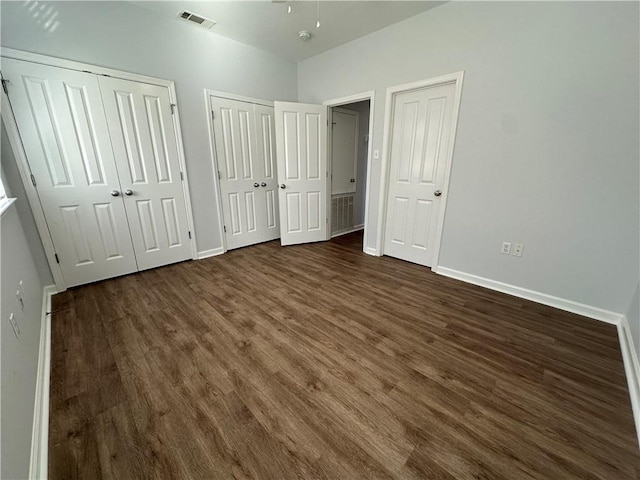 unfurnished bedroom featuring multiple closets and dark hardwood / wood-style floors