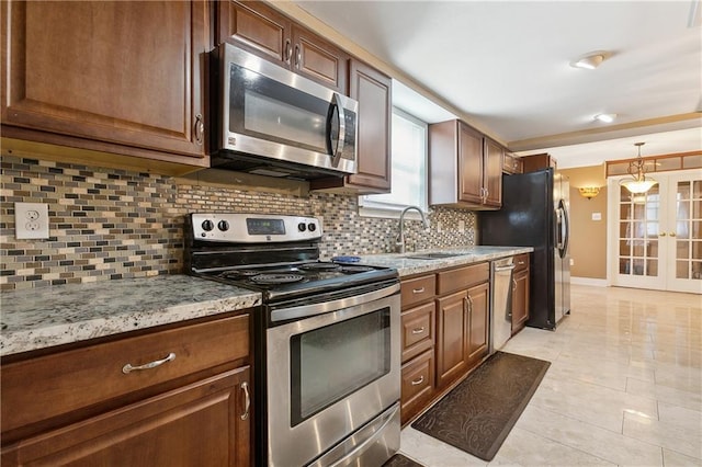 kitchen with light stone countertops, tasteful backsplash, appliances with stainless steel finishes, and sink