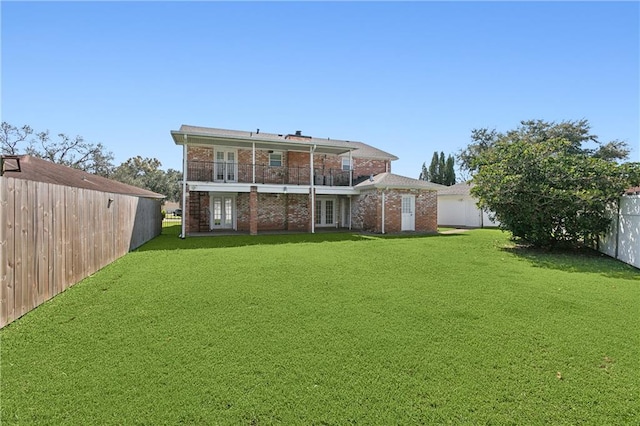 back of house featuring a balcony and a lawn