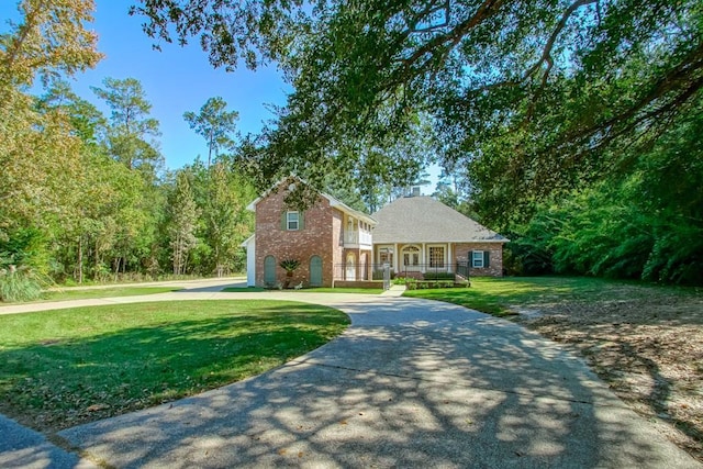 traditional-style home featuring brick siding, curved driveway, and a front yard
