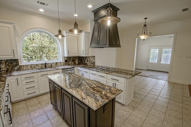 kitchen with tasteful backsplash, decorative light fixtures, light stone counters, and a kitchen island