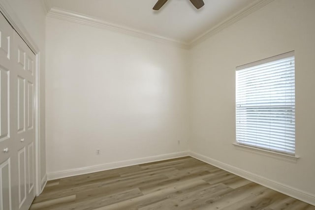 empty room with ornamental molding, light wood finished floors, a ceiling fan, and baseboards