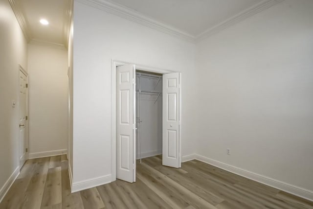 unfurnished bedroom featuring crown molding, a closet, baseboards, recessed lighting, and wood finished floors