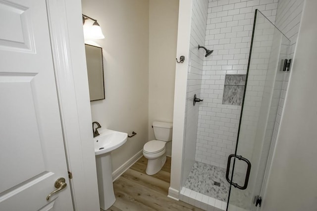 bathroom with toilet, wood finished floors, and a shower stall