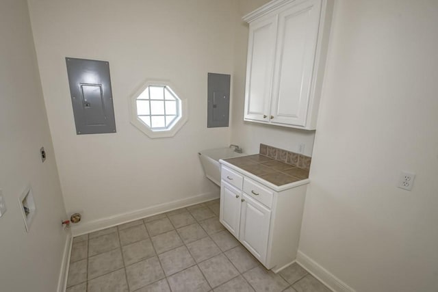 clothes washing area featuring a sink, electric panel, cabinet space, and baseboards