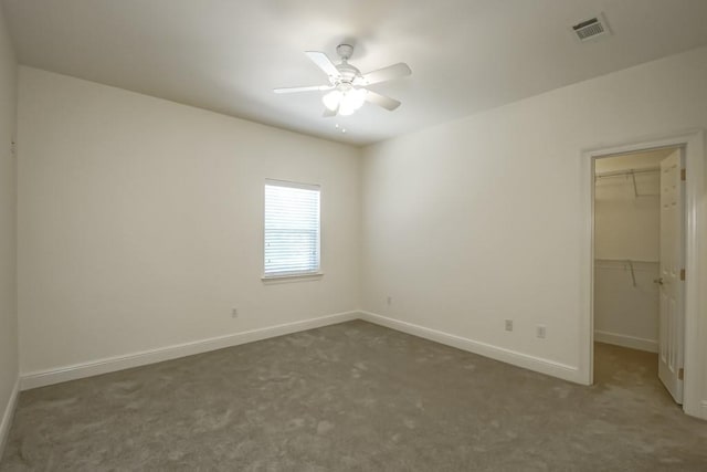 empty room featuring ceiling fan and dark colored carpet