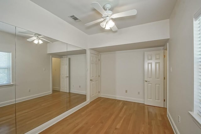unfurnished bedroom featuring baseboards, visible vents, wood finished floors, and a closet