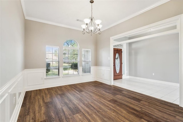 spare room with crown molding, a chandelier, and hardwood / wood-style floors