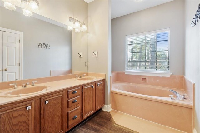 bathroom featuring vanity, an inviting chandelier, hardwood / wood-style floors, and a washtub