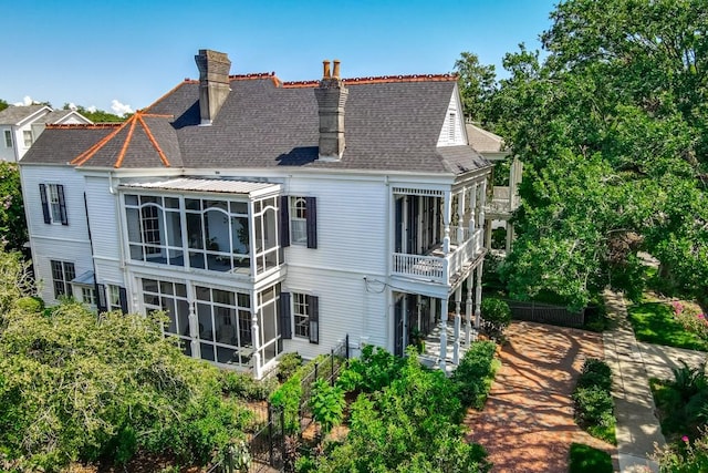 back of property with a balcony and a sunroom