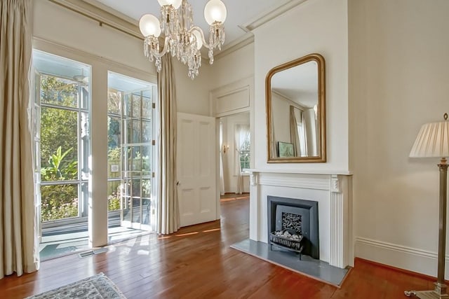 entryway featuring a notable chandelier, wood-type flooring, and ornamental molding