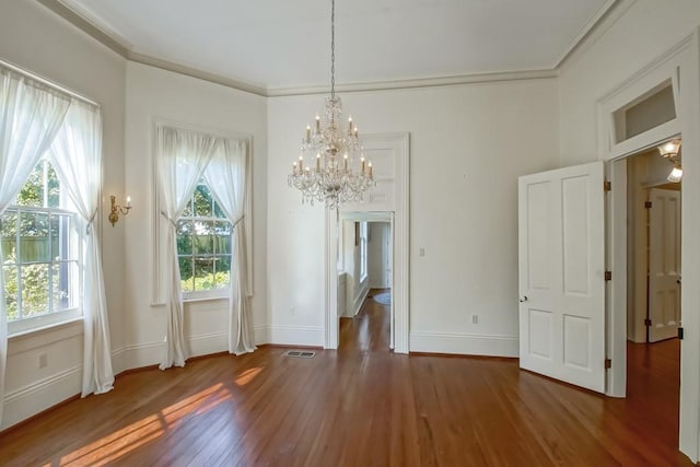 unfurnished dining area with ornamental molding, dark hardwood / wood-style flooring, and an inviting chandelier