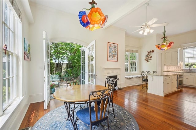 dining space featuring beam ceiling, sink, hardwood / wood-style floors, ceiling fan, and crown molding