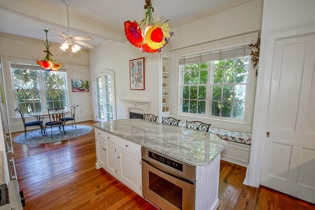 kitchen with oven, white cabinetry, hardwood / wood-style floors, and a wealth of natural light