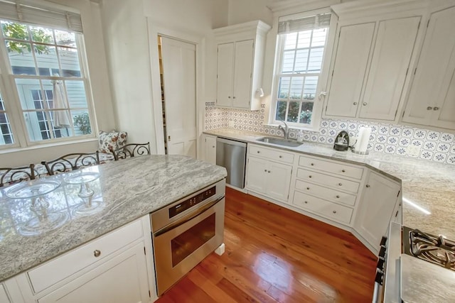 kitchen with sink, appliances with stainless steel finishes, white cabinetry, and backsplash