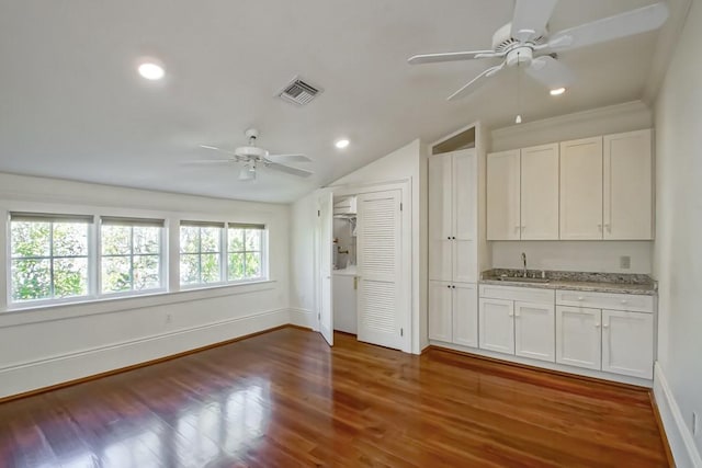 interior space featuring white cabinetry, hardwood / wood-style flooring, sink, and vaulted ceiling