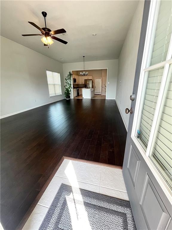 unfurnished living room featuring ceiling fan with notable chandelier and light hardwood / wood-style floors