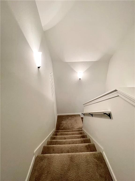 stairway featuring lofted ceiling and carpet floors