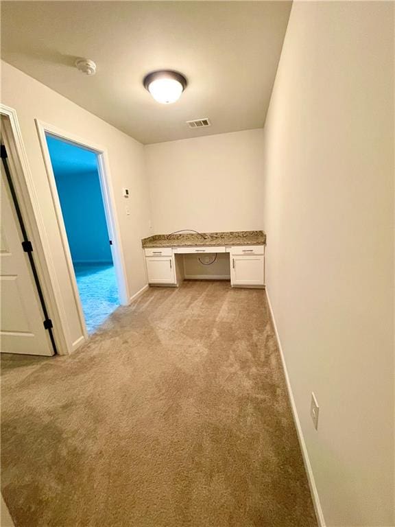 interior space with built in desk and light colored carpet