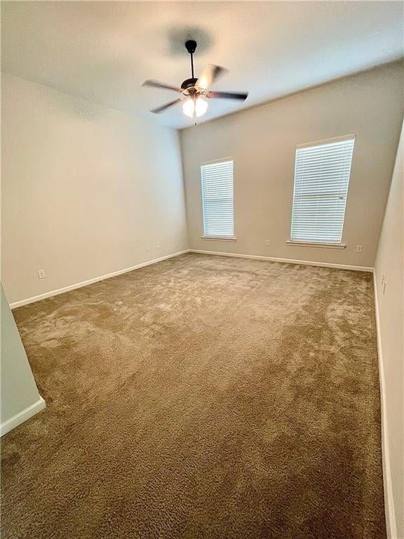 unfurnished room with ceiling fan and dark colored carpet