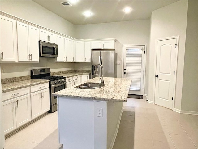 kitchen with light stone counters, white cabinetry, a kitchen island with sink, sink, and stainless steel appliances