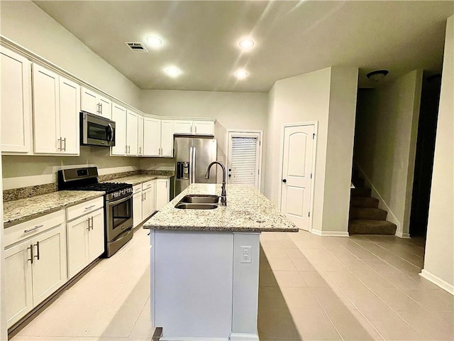 kitchen with light stone counters, white cabinetry, a kitchen island with sink, sink, and stainless steel appliances