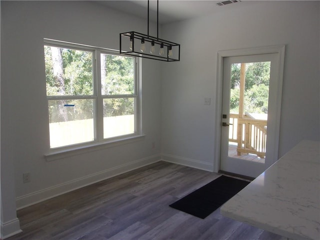 unfurnished dining area featuring dark wood-type flooring and a healthy amount of sunlight