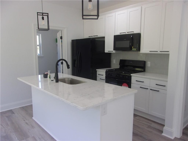 kitchen with sink, black appliances, a kitchen island with sink, and white cabinetry