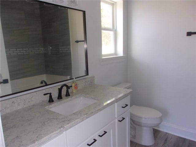 bathroom with vanity, hardwood / wood-style floors, toilet, and tiled shower