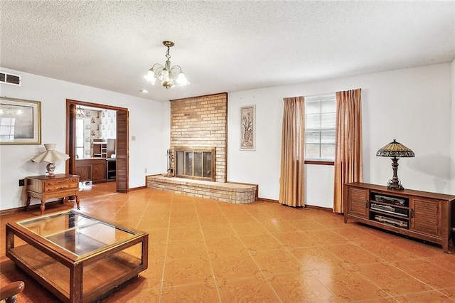 living room featuring a textured ceiling, a brick fireplace, and a notable chandelier