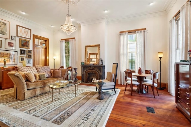 living area featuring a chandelier, crown molding, dark hardwood / wood-style flooring, and plenty of natural light