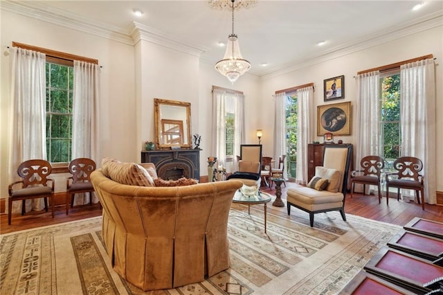 sitting room with a wealth of natural light, a chandelier, crown molding, and hardwood / wood-style flooring